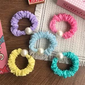 Lot de 5 chouchous colorés en tissu avec perles blanches sur fond en bois rustique