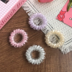 Set of 4 colorful spiral hair ties in lavender pink and cream on a wooden desk