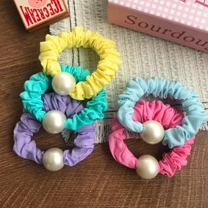 Lot de chouchous pastels avec perles sur table en bois et set de table à franges