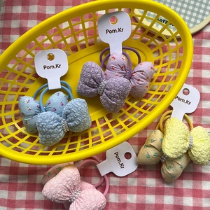 Detalle de gomas para el pelo con lazos florales y perlas en una cesta amarilla