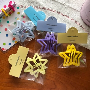 Détail de barrettes étoiles pailletées multicolores avec leur emballage individuel