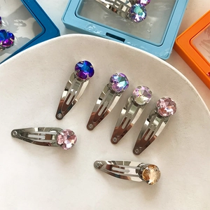 Gros plan de barrettes à cheveux colorées en cristal sur une assiette blanche