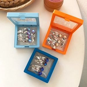 Boîtes de rangement portables bleues et orange avec des barrettes à strass colorés