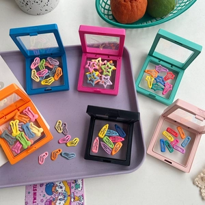 Colorful bone and star-shaped pet hair clips in transparent storage cases on a tray