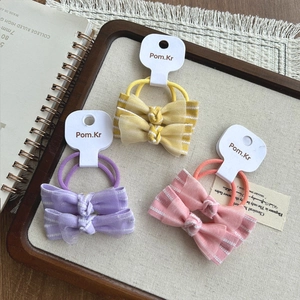 Vue détaillée des chouchous nœuds en dentelle jaune, violet et rose sur plateau
