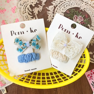 Lace and pearl bow hair clips set for kids on card inside a yellow basket