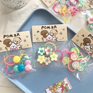 Close-up of assorted kids hair ties with floral and bow charms in pastel blue tray