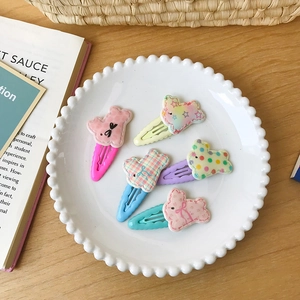 Détail de cinq barrettes à cheveux aux couleurs macaron avec pois et nœuds dans une assiette