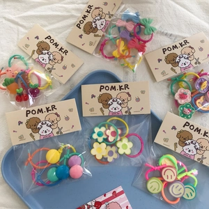 Colorful kids hair ties set with cute flower, bear and smiley face charms on blue tray