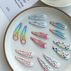 Close-up of 12 colorful water-drop BB clips with heart and star prints on ceramic tray