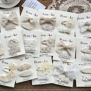Lot de barrettes à cheveux en dentelle et perles présentées sur un tapis tressé