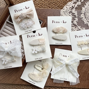 Détail de barrettes en dentelle avec perles et broderies de fleurs sur cartes