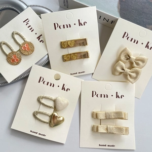 Détail de barrettes dorées à paillettes en forme de cœur et nœud sur cartes