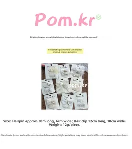 Detailed view of handmade lace bow and pearl flower hair clips on white card packaging