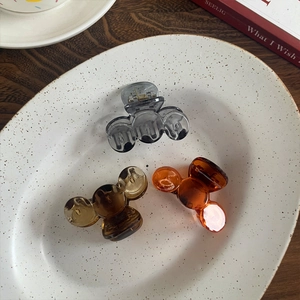 Three elegant translucent shark hair clips in grey, brown, and orange on a ceramic tray