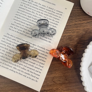 Three translucent bubble hair claws in grey, tea, and amber on an open vintage book