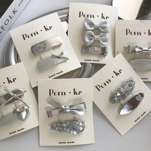 Détails de pinces à cheveux en cuir argenté avec nœuds et cœurs sur cartes