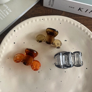 Detailed view of three mini acrylic shark hair claws in amber and grey on a ceramic tray
