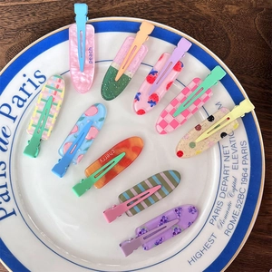 Close-up of colorful fruit pattern acrylic hair clips on a decorative ceramic plate