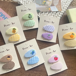 Detailed view of handmade fruit embroidery BB hair clips on a cozy wooden setting