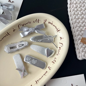 Coffret de barrettes argentées avec nœud et cœurs scintillants sur plateau décoratif