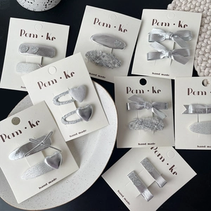 Détail de barrettes nœud argentées et épingles cœur en tweed sur une assiette