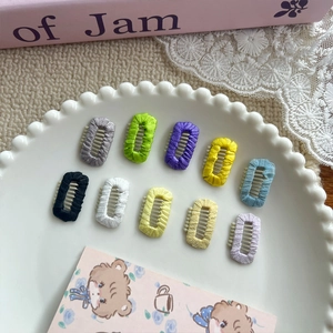 Set of 10 colorful candy-colored mini dog hair clips in a white ceramic dish