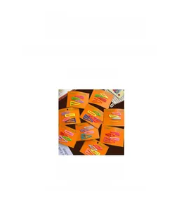 Set of 10 colorful metal hair clips in teardrop and square shapes on an orange card