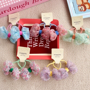 Set of five floral bow hair ties in sky blue, pink, and purple on a woven background