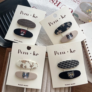 Détail montrant le motif chat brodé à la main et le set de barrettes à carreaux