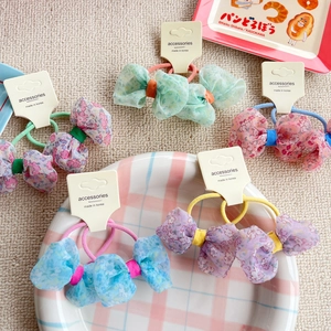 Detailed flat lay of floral chiffon bow hair ties set on a beige textured mat