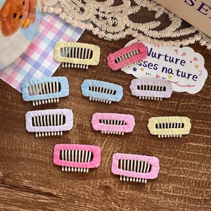 Set of 10 macaron-colored mini hair clips and combs on a dark wood background