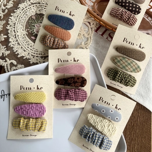 Detail of assorted fabric hair clips featuring plaid and floral patterns on cards