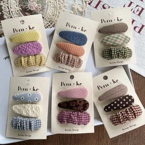 Detail of assorted fabric teardrop hair clips with plaid and floral patterns for girls