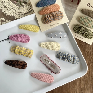 Detail of Korean style plaid and floral fabric hair clips in various colors and patterns