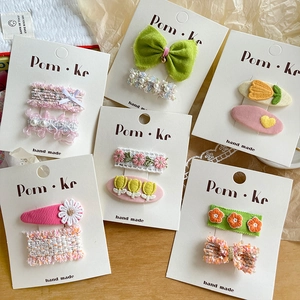 Detail of handmade floral lace and knit bow hair clips on white display cards