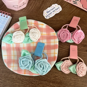 Elastic rose flower hair ties with green leaves on a stylish ceramic plate