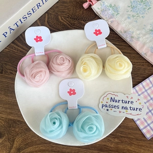 Détail de trois chouchous roses en résille aux tons pastel sur une carte faite à la main