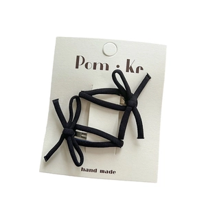 Elegant set of two black fabric knotted bow hair clips on a white display card