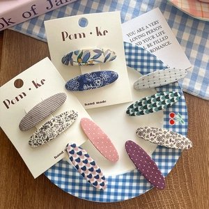 Floral print and polka dot fabric BB hair clips set on a stylish ceramic display plate