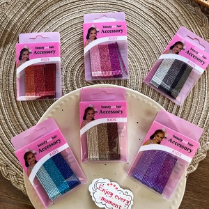 Detail view of 6 boxes of colorful glitter bobby pins for girls on a woven display tray
