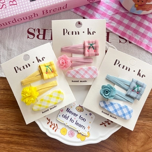 Three sets of handmade fabric hair clips with floral, checkered, and cherry embroidery
