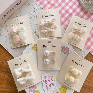 Elegant six-pair set of cream pearl bow hair clips for girls in a floral ceramic plate