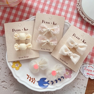 Creamy pearl bow hair clips for girls displayed on a stylish card and white plate