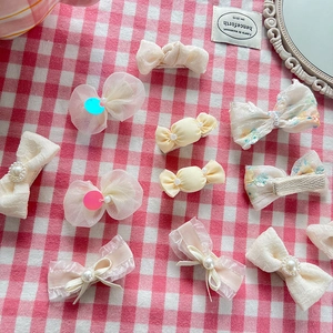 Close-up of cream bow hair clips with pearls and lace on a checkered background