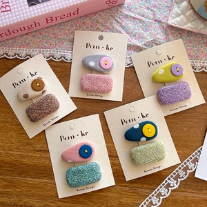 Close-up of fabric hair clips with polka dots and tweed buttons on display cards