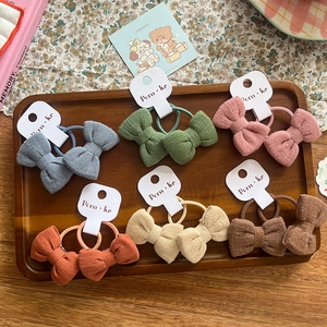 Lot de six chouchous en tissu avec nœuds colorés bleu vert et rose sur un plateau