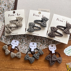 Close-up of handmade plaid bow hair clips and scrunchies in autumn brown and black patterns