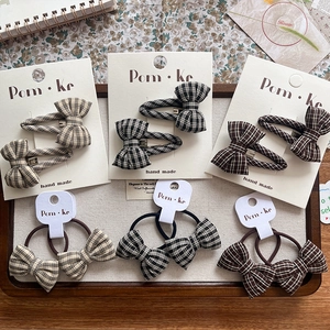 Detail of plaid bow hair clips and ties set on wooden tray with handmade cards