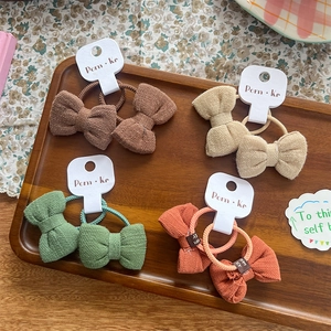 Lot de quatre chouchous nœuds en tissu texturé aux couleurs marron, beige, vert et orange